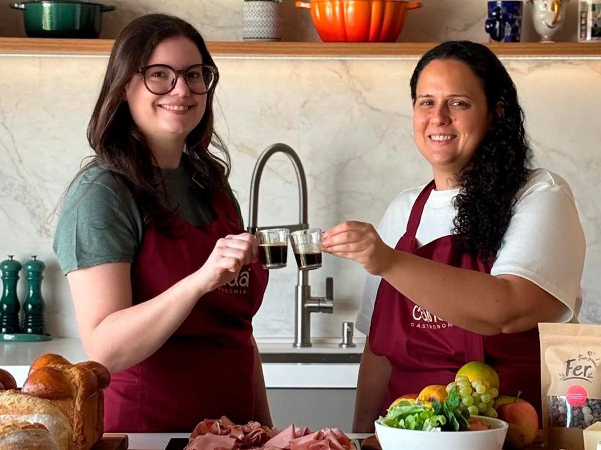 Sócias do Candá Gastronomia brindindo com café na cozinha do restaurante